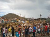 破壊された町で支援物資の配給を待つ人々